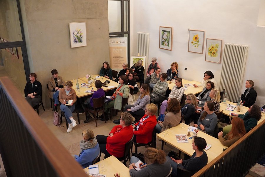 Ein Publikum sitzt an Tischen und nimmt an einem Workshop teil.