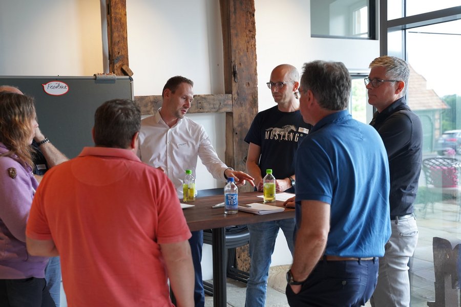 Workshopteilnehmende stehen um einen Tisch herum und tauschen sich untereinander aus.